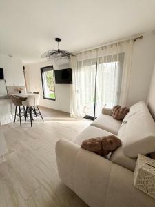 a white living room with a couch and a table at Le Refuge Douillet à 10min de Disneyland avec Parking Privé et Belle terrasse vue sur Jardin in Coupvray