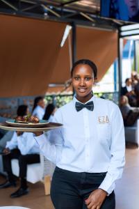 a woman in a bow tie holding a plate of food at Eza Hotel in Kigali +284 photos