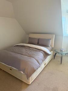 a bed in a white room with a table at Cosy House in Reading