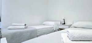 a white room with three beds with white sheets at Speloncae Apartment in Sperlonga