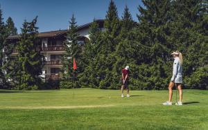 two people playing golf on a golf course at Hotel Waldhuus in Davos