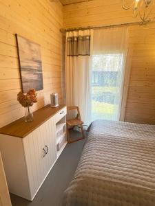 a bedroom with a bed and a desk and a window at Māja pie Ziedu laivas in Plieņciems