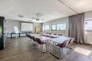 a conference room with a white table and chairs at MEININGER Hotel Berlin Airport in Berlin
