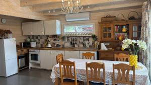 a kitchen with a table with chairs and a white refrigerator at Māja pie Ziedu laivas in Plieņciems +11 photos