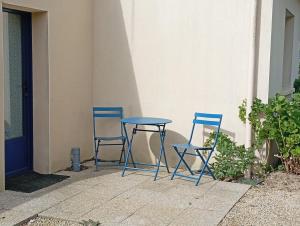 two blue chairs and a table next to a building at Le studio des pins in Plouézec +3 photos