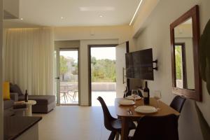 a living room with a table with chairs and a television at SUMU Luxury Apartment in Lefkada