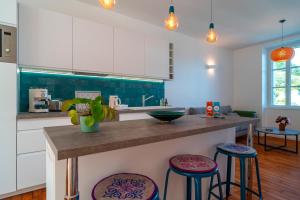 a kitchen with white cabinets and purple stools at Lumineux logement vue sur le port in Audierne +9 photos