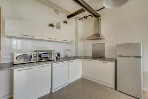 a white kitchen with white cabinets and a microwave at Les LILAS in Les Lilas +3 photos