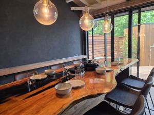 a dining room with a wooden table with chairs and lights at 海と森と宿 - mina-to - in Futtsu