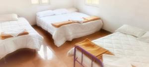 a room with two beds with white sheets at Prysm Homestay - Kotagiri in Kotagiri