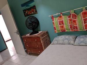 a bedroom with a bed and a fan on a dresser at CASA ESTRELA e SOL in Barra de Jacuípe