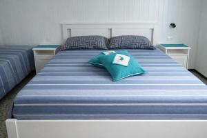 a large bed with a blue and white striped blanket at Domos Ventuno Barumini in Barùmini