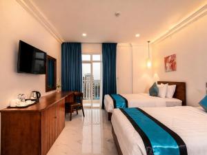 a hotel room with two beds and a desk and a television at Le Kree Downtown Hotel in Phnom Penh