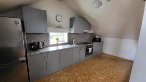 a kitchen with white cabinets and a clock on the wall at Apartmán u kolejí D in Kašnice