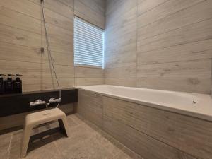 a bathroom with a tub and a stool in it at 海と森と宿 - mina-to - in Futtsu