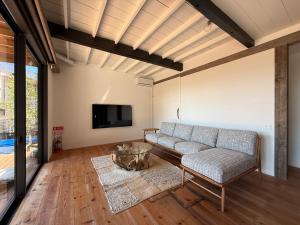 a living room with a couch and a tv at 海と森と宿 - mina-to - in Futtsu