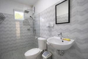 a bathroom with a white toilet and a sink at Heidi's Guesthouse in Siquijor