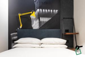 a bed with white pillows and a yellow light above it at Hotiday Milano Risorgimento in Milan
