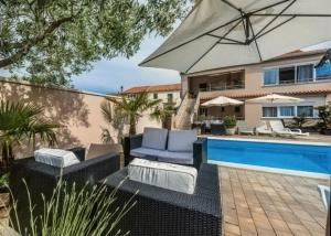 a patio with chairs and an umbrella next to a pool at Apartments A&A in Bibinje