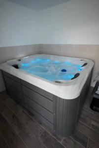 a hot tub with blue water in a bathroom at Fully equipped, independent apartment in Marles-en-Brie +1 photo