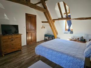 a bedroom with a bed with a television and a dresser at La Tilia in Saint-Riquier