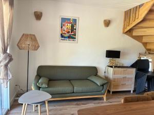 a living room with a green couch and a table at Maison/appartement proche Cala Rossa in Lecci
