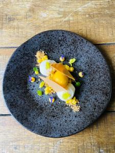 a black plate with food on a wooden table at The Kings Arms - Fleggburgh with Hot tub in Burgh Saint Margaret