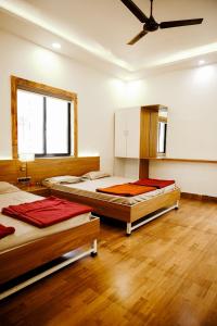 two beds in a room with wooden floors and a ceiling at Harmony Hills Ecostay in Nasrāpur