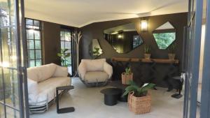 a living room with two white chairs and a mirror at The House On The Hill in Lanseria