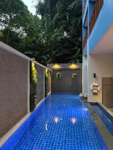 a swimming pool in a house with a blue tile floor at Golden Paradise Hotel - SHA PLUS in Karon Beach