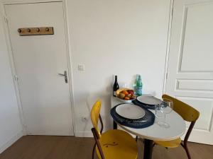 a table with two yellow chairs and a table with glasses at Résidence du Loir - Le Petit Loft in Vendôme +3 photos