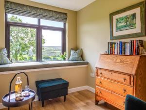 a window seat in a room with a table and a dresser at Greenhill in Blackwaterfoot