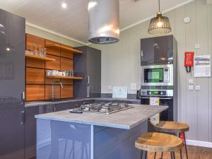 a kitchen with a stove top island with two stools at Whitey Top Country Lodge in Pentridge +18 photos