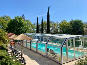 a pool in a glass house with chairs and an umbrella at Gîtes de la Roullière in Le Longeron