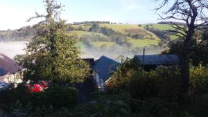 Blick auf ein nebliges Tal mit einem Haus und Bäumen in der Unterkunft Rhiwiau Self Catering in Carmarthen