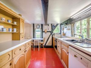 a kitchen with wooden cabinets and a red floor at Glebe Cottage in Powick