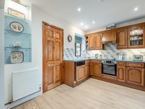a kitchen with wooden cabinets and a stove top oven at Melancroft in Llanfihangel-nant-Melan
