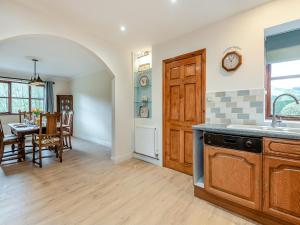 a kitchen and dining room with a table and a clock at Melancroft in Llanfihangel-nant-Melan