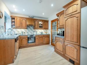 a large kitchen with wooden cabinets and a sink at Melancroft in Llanfihangel-nant-Melan +15 photos