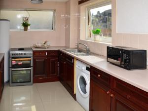 a kitchen with a sink and a stove and a microwave at St Mary's Crescent House in Stanwell