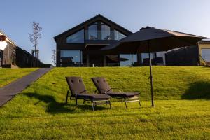 two chairs and an umbrella in front of a house at Ferienhaus SUNSHINE am Mühlfeldsee in Löbnitz