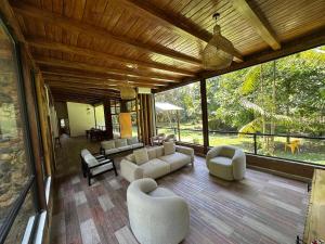 a living room with couches and chairs and a large window at Boana Explora Pachijal in Pedro Vicente Maldonado