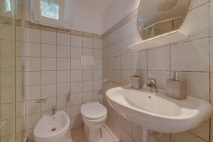 a white bathroom with a sink and a toilet at Il Boschetto sul Mare - Goelba in Capoliveri +24 photos