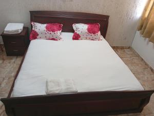 a bed with white sheets and red pillows at Johannys'co in Abidjan