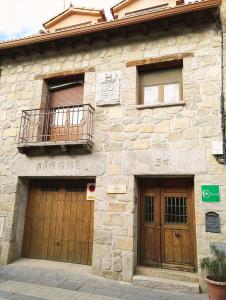 Edificio de piedra con 2 puertas y balcón en Casa Rural La Vid, en Cadalso de los Vidrios