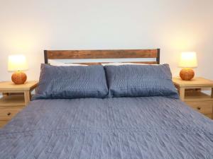 a bed with blue sheets and two lamps on tables at Trelowen in Wadebridge