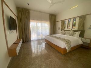 a bedroom with a large bed and a flat screen tv at Misty Glen in Vagamon
