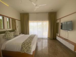 a bedroom with a large bed and a flat screen tv at Misty Glen in Vagamon