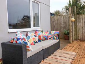 a wicker couch with colorful pillows on a patio at Trelowen in Wadebridge