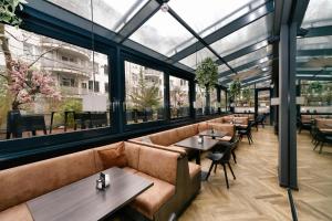a restaurant with couches and tables and windows at Hotel ZOE by AMANO in Berlin